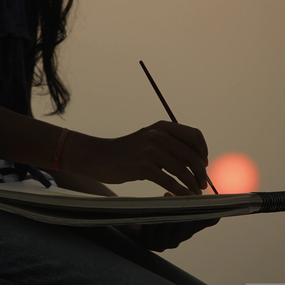 Billede af en kvinde der tegner i solnedgangen