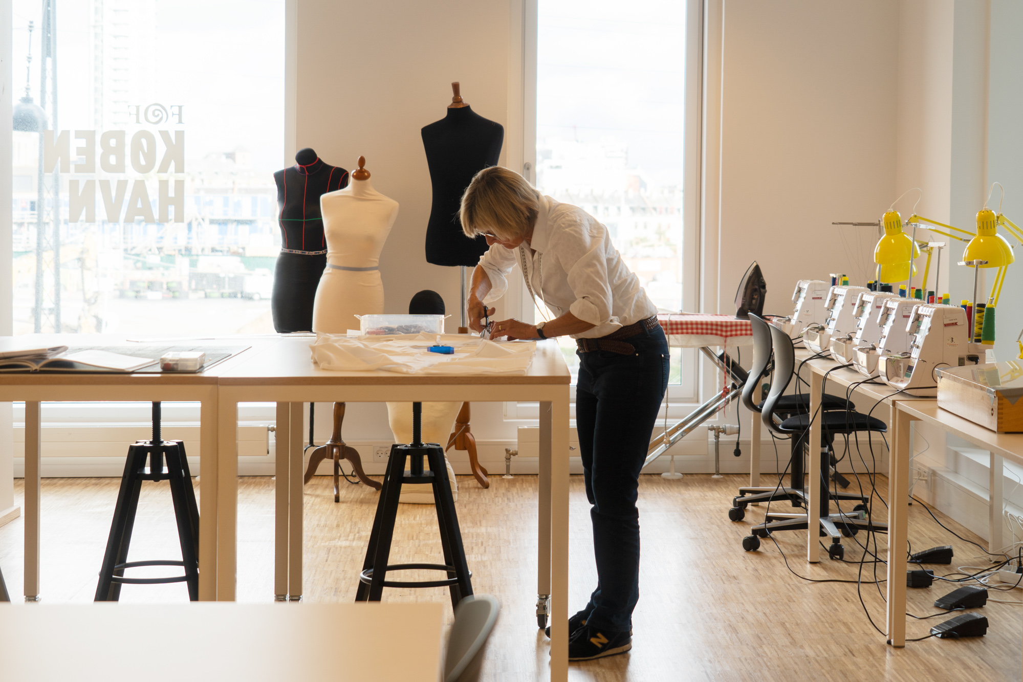 Kursist syr tøj ved symaskine under kursus i syning og tilskæring.