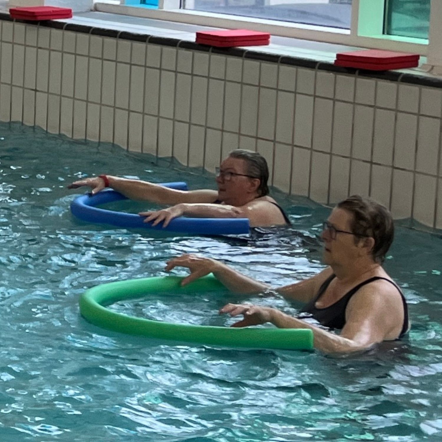 Kvinder der laver øvelser med skumnudler i vandbassin iført badedragter