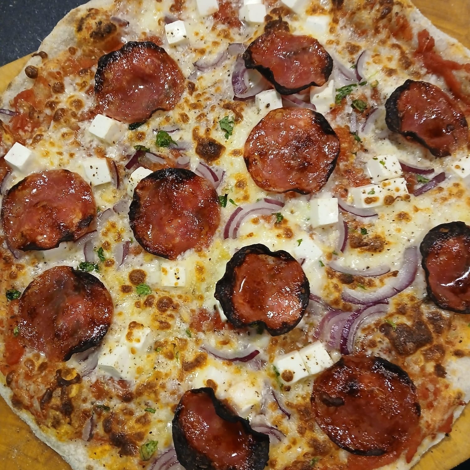 Hjemmelavet pizza med sauce, pepperoni, rødløg og ost