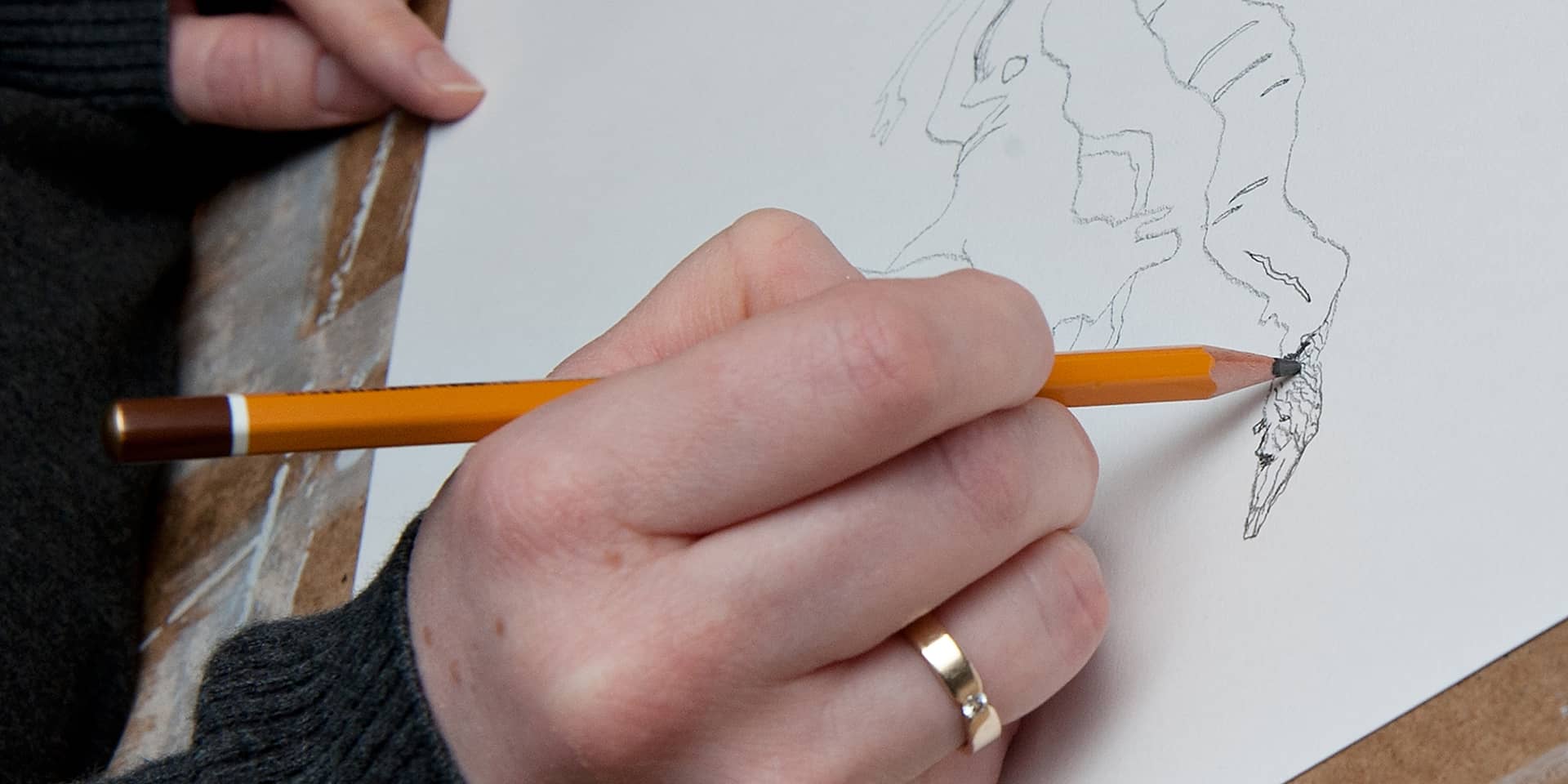 Hænder, der tegner med en gul blyant, på tegnekursus for begyndere og øvede i FOF Aarhus