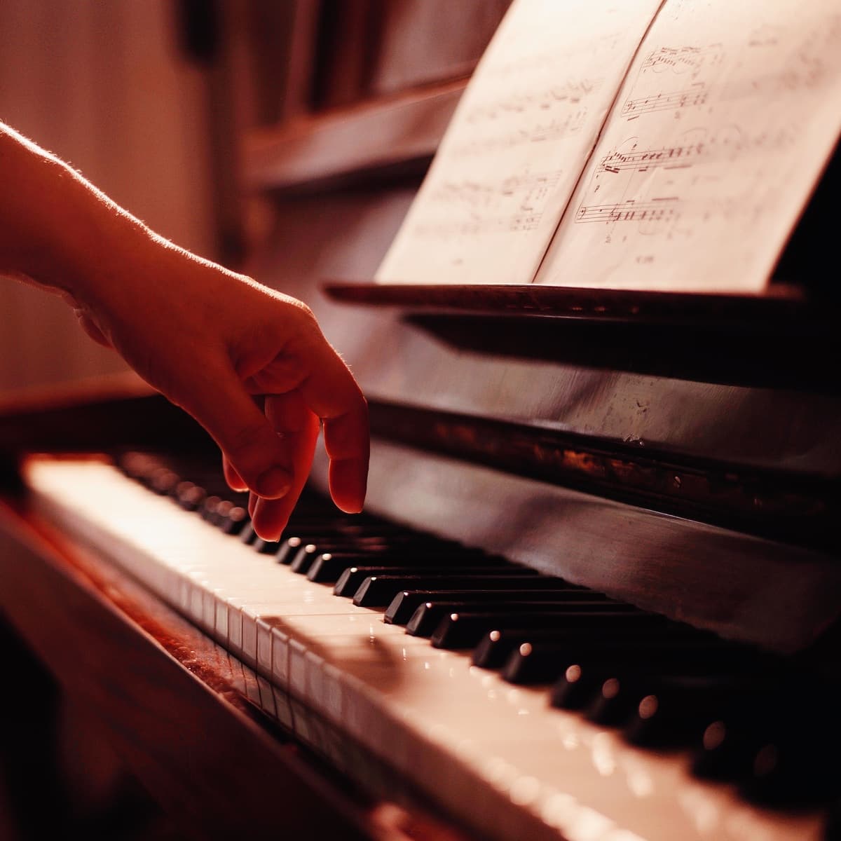 en hånd spiller på klavertangenter foran et nodeark under varm belysning på FOF’s klaverkursus i Aalborg