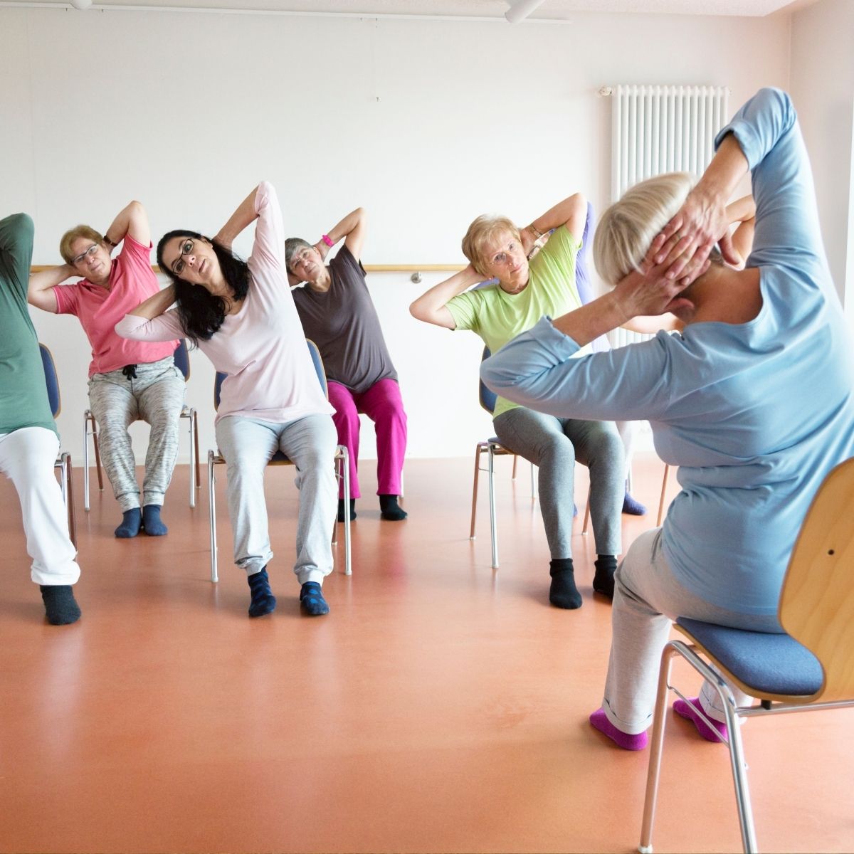Instruktør guider deltagere i stolegymnastikøvelser