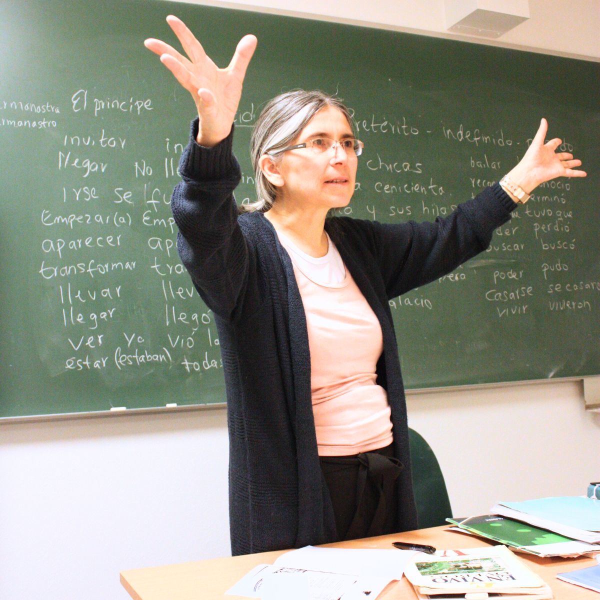 Spanskunderviser der står foran tavlen med spredte arme