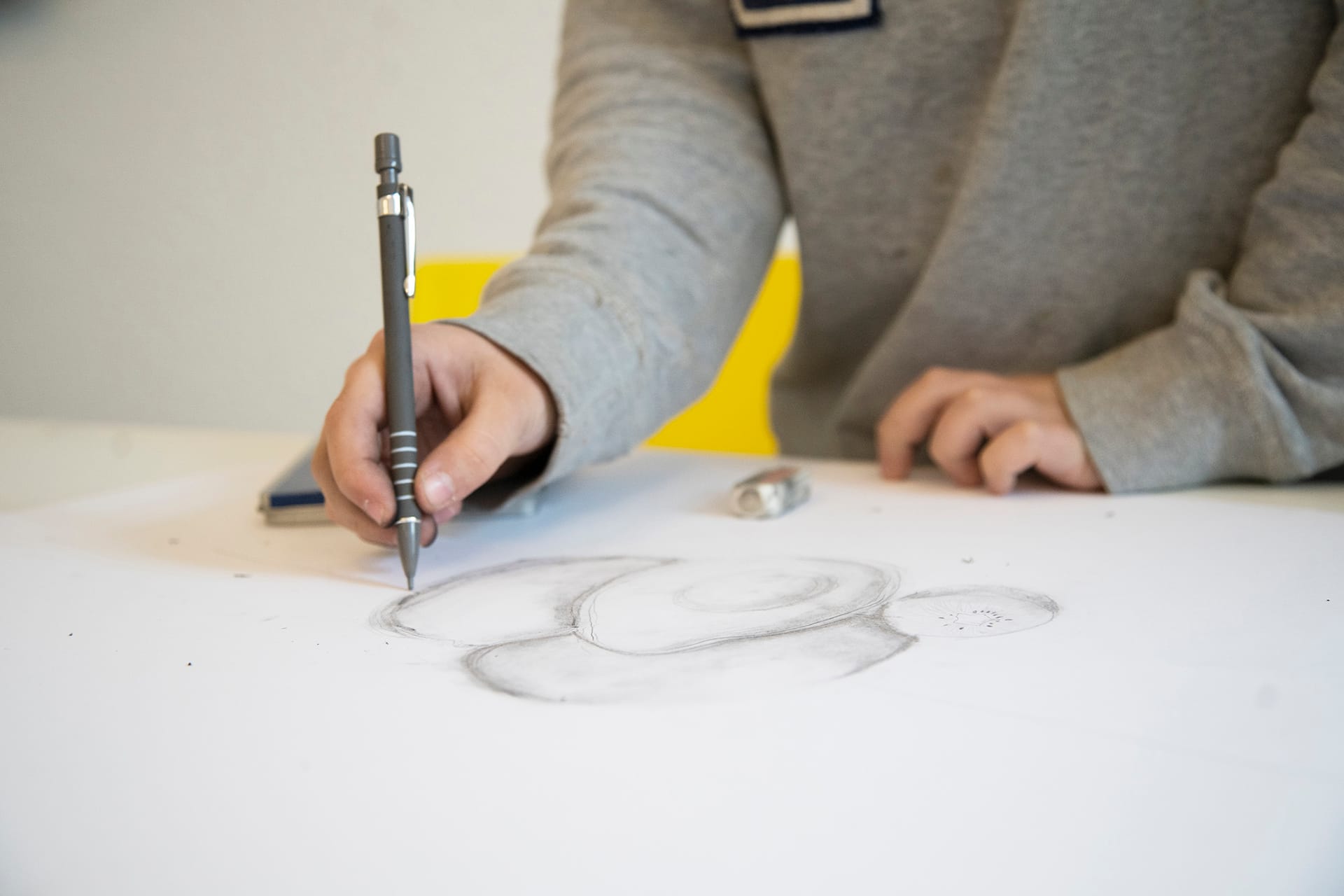 Barn tegner med blyant ved bord