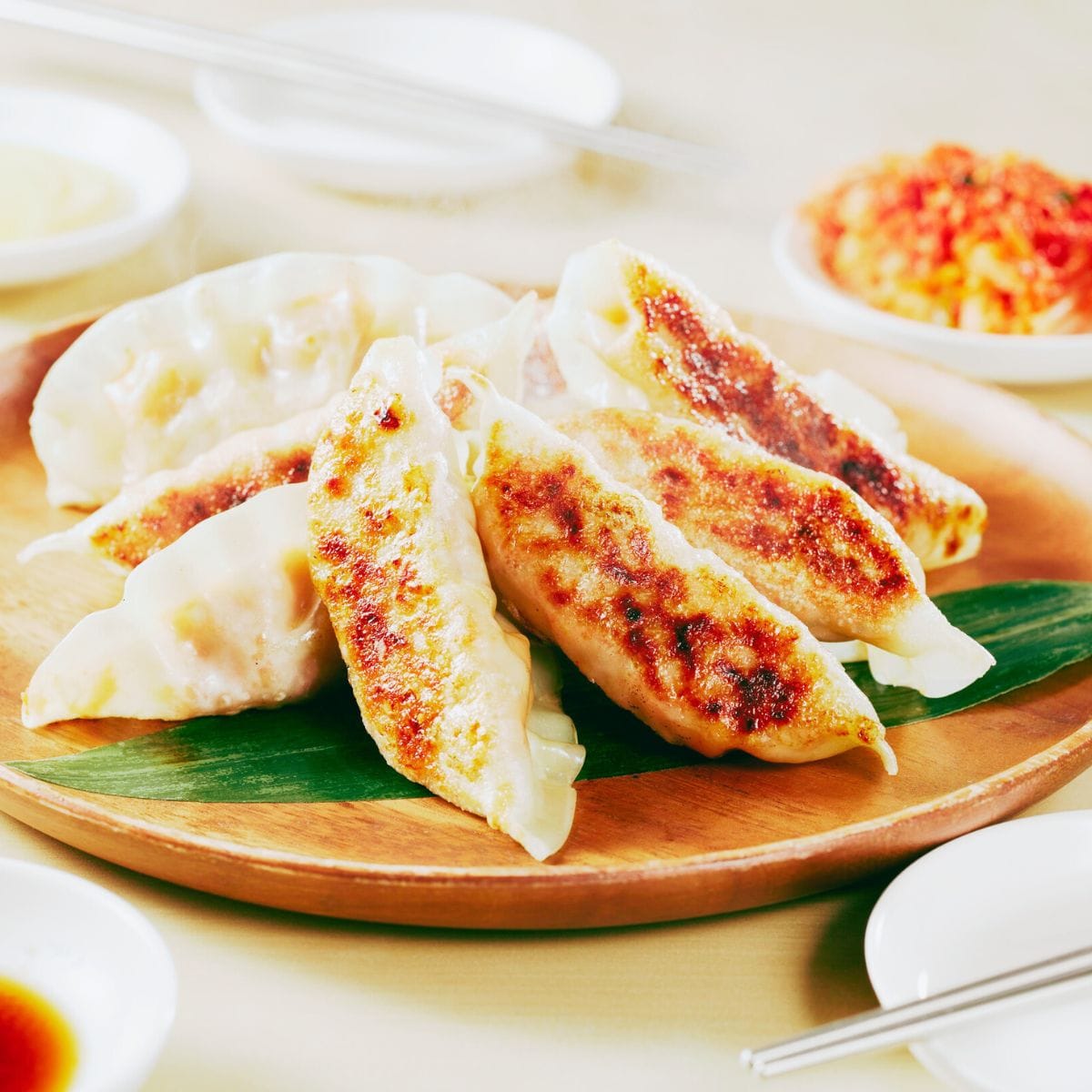 Deltager folder japanske dumplings og gør klar til servering med hjemmelavede dip-saucer