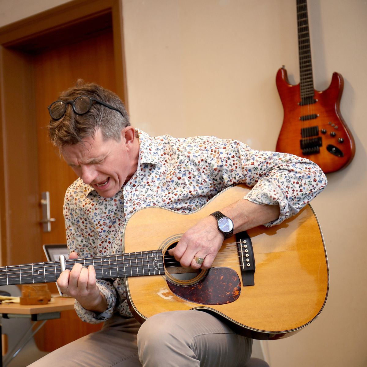 Person spiller akustisk guitar på musikhold hos FOF.