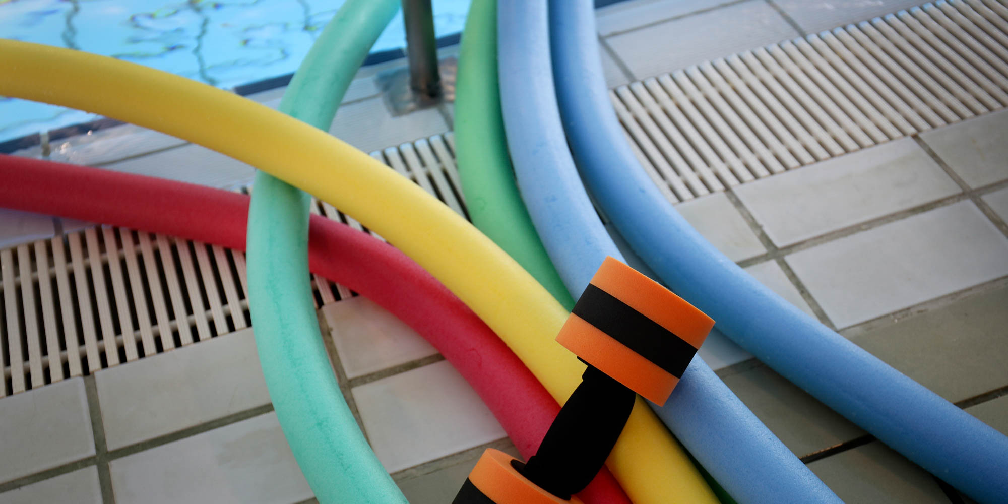 Farvede poolnudler og skumredskaber ved bassin