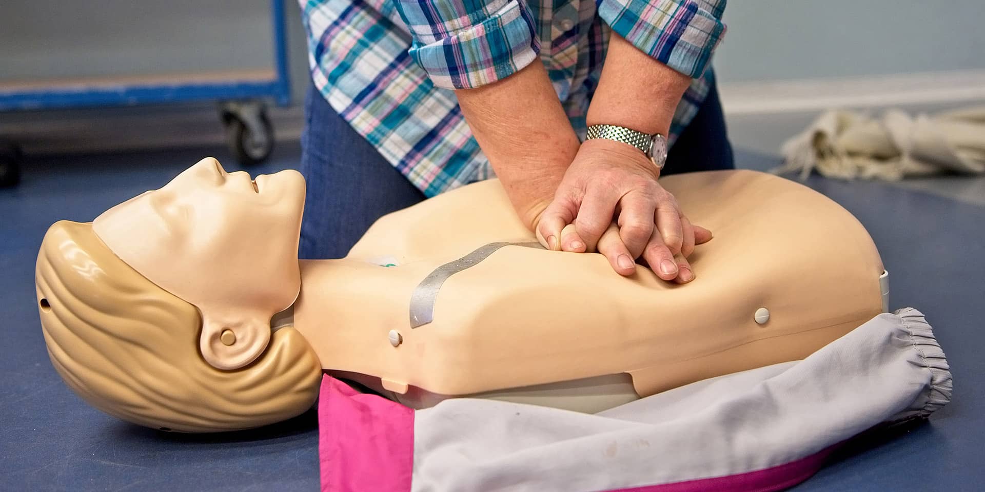 Underviser i førstehjælp i FOF Aftenskolen Aarhus illustrerer hjertemassage på en dukke
