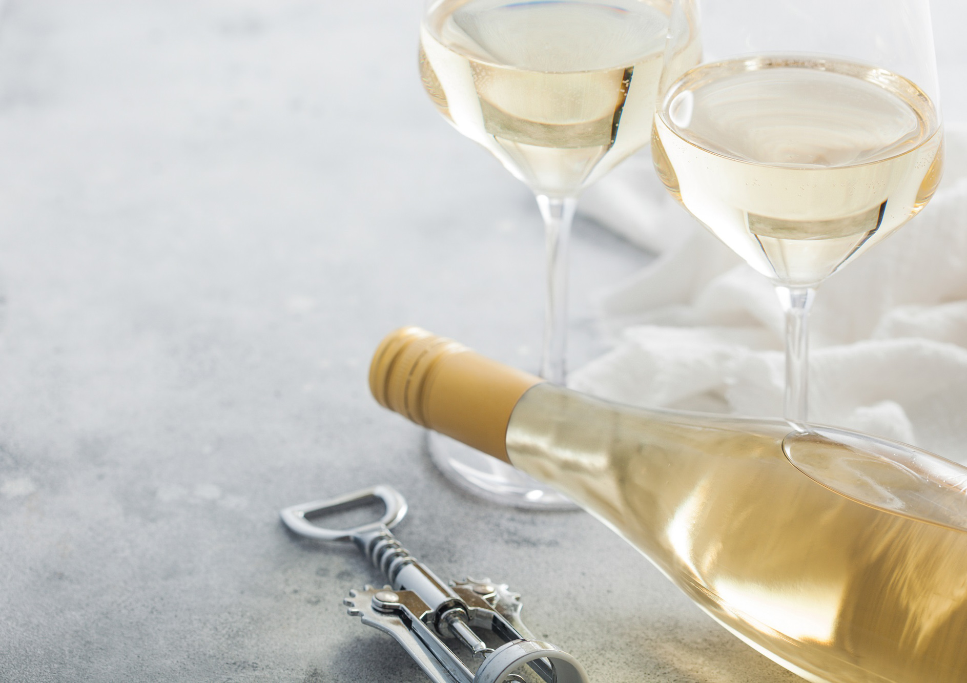 En liggende flaske hvidvin og to fyldte glas. Smagning af Alsace Riesling på højt niveau hos FOF København og Nordsjælland.