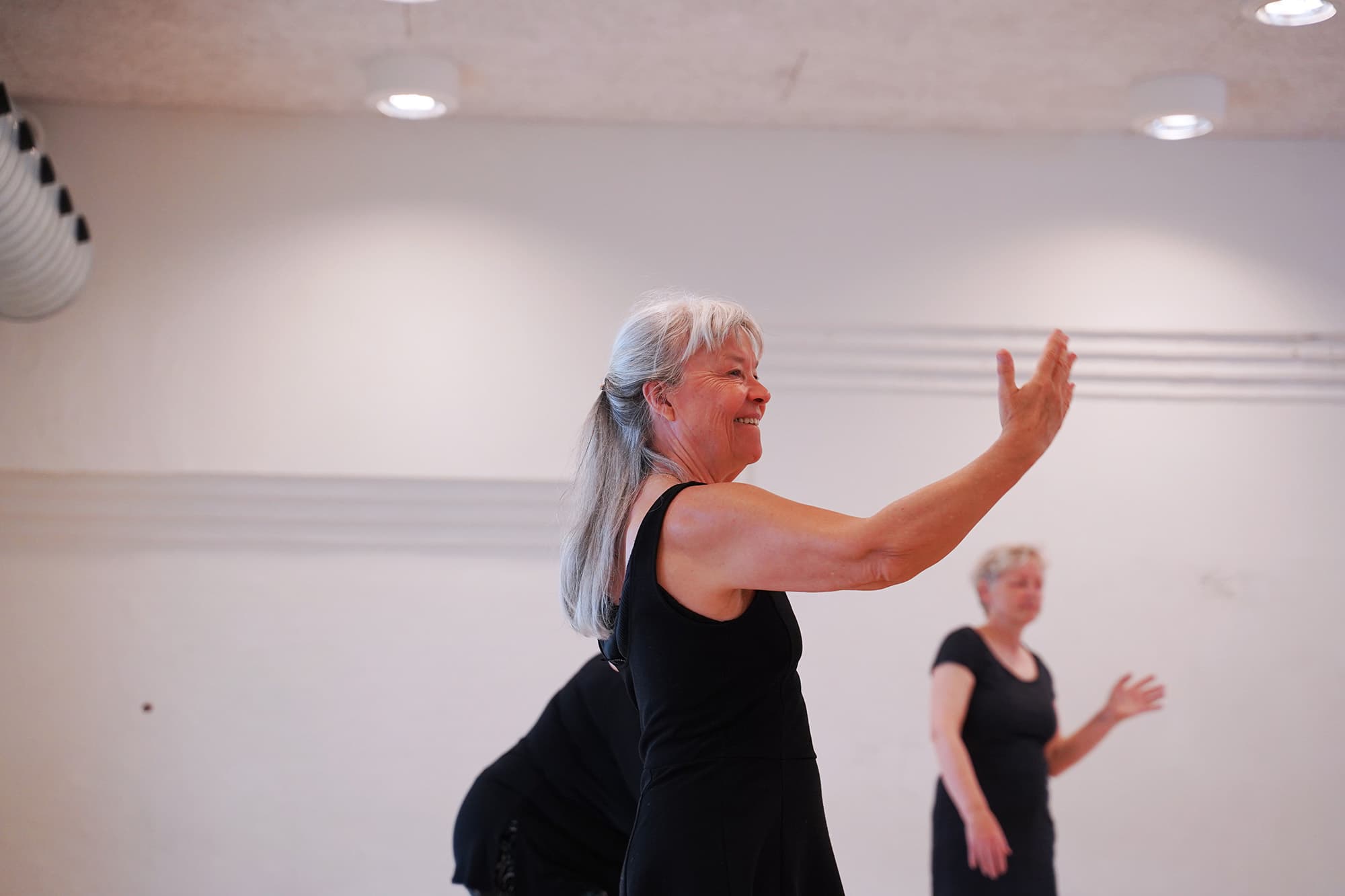 Kvinder danser salsa-motion i holdsal med smil og energi