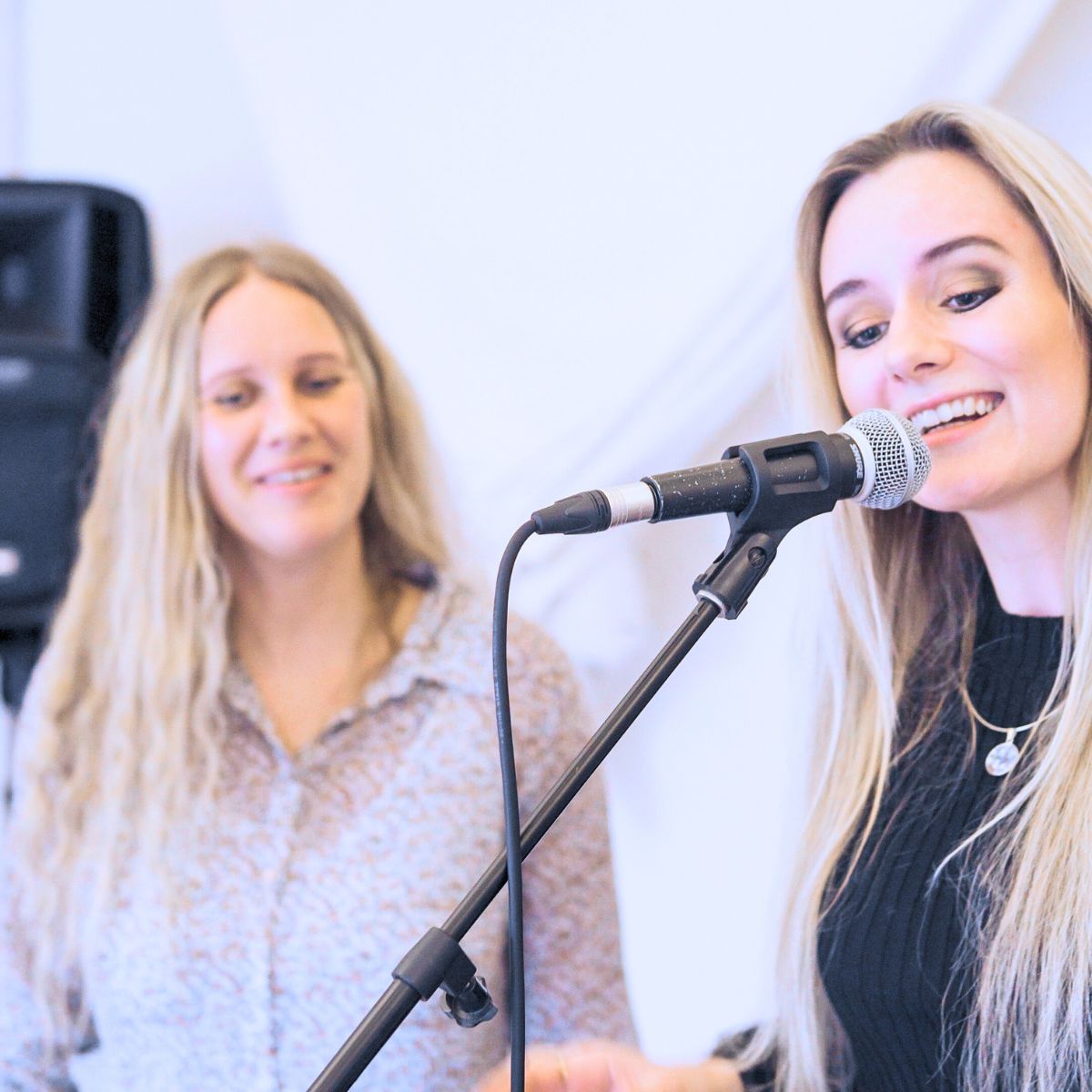 pige der synger i mikrofon, med underviser bag sig