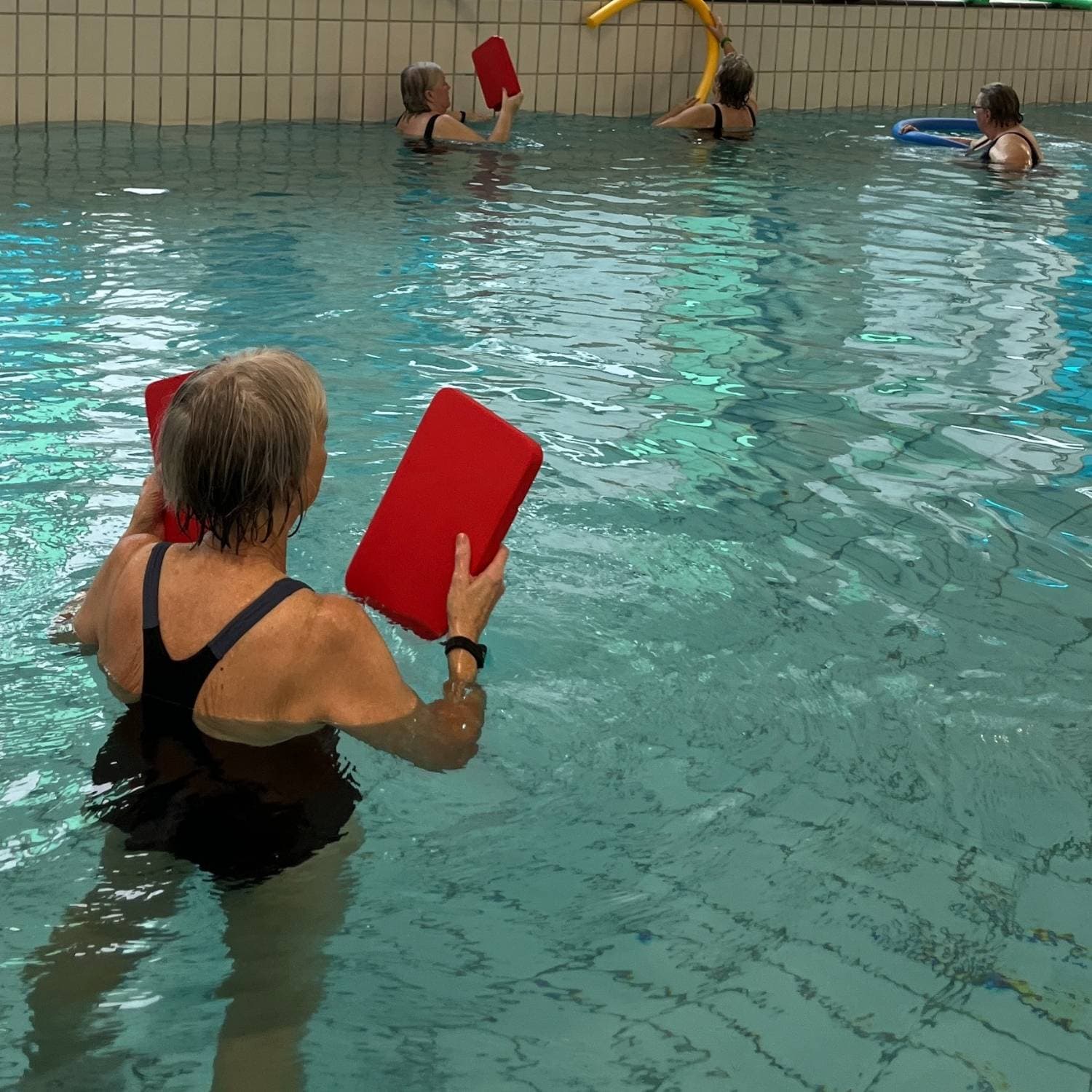 Kursister der laver øvelser med skumklodser i bassin i svømmehallen