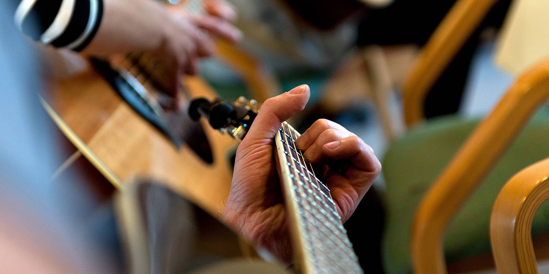 Et udsnit af en guitar (zoom ind) og hænder, der spiller på guitaren til kursus i FOF Aarhus, greatest hits på guitar for øvede.
