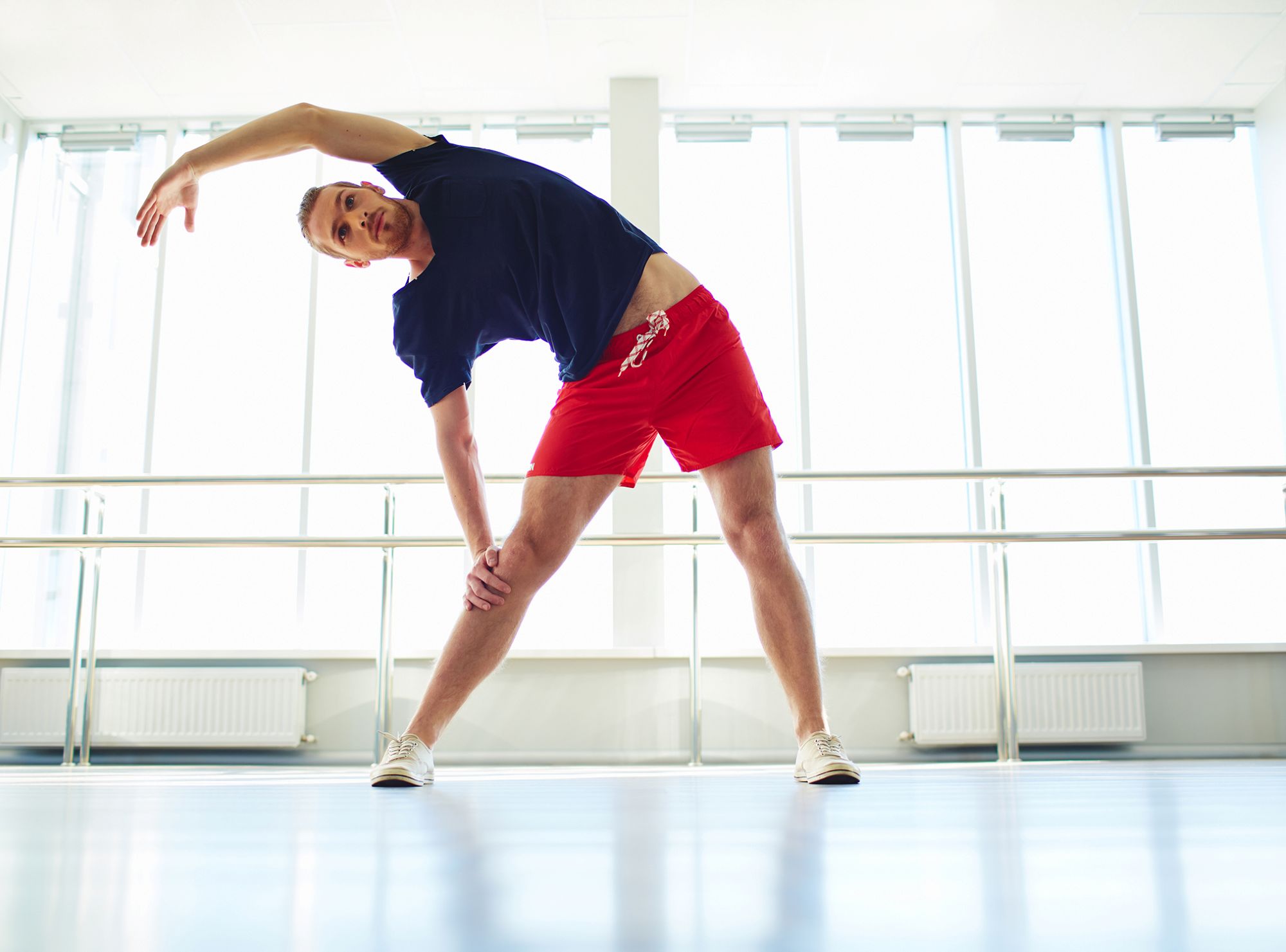 Mand udøver yoga i stående stræk på et sommerhold for mænd
