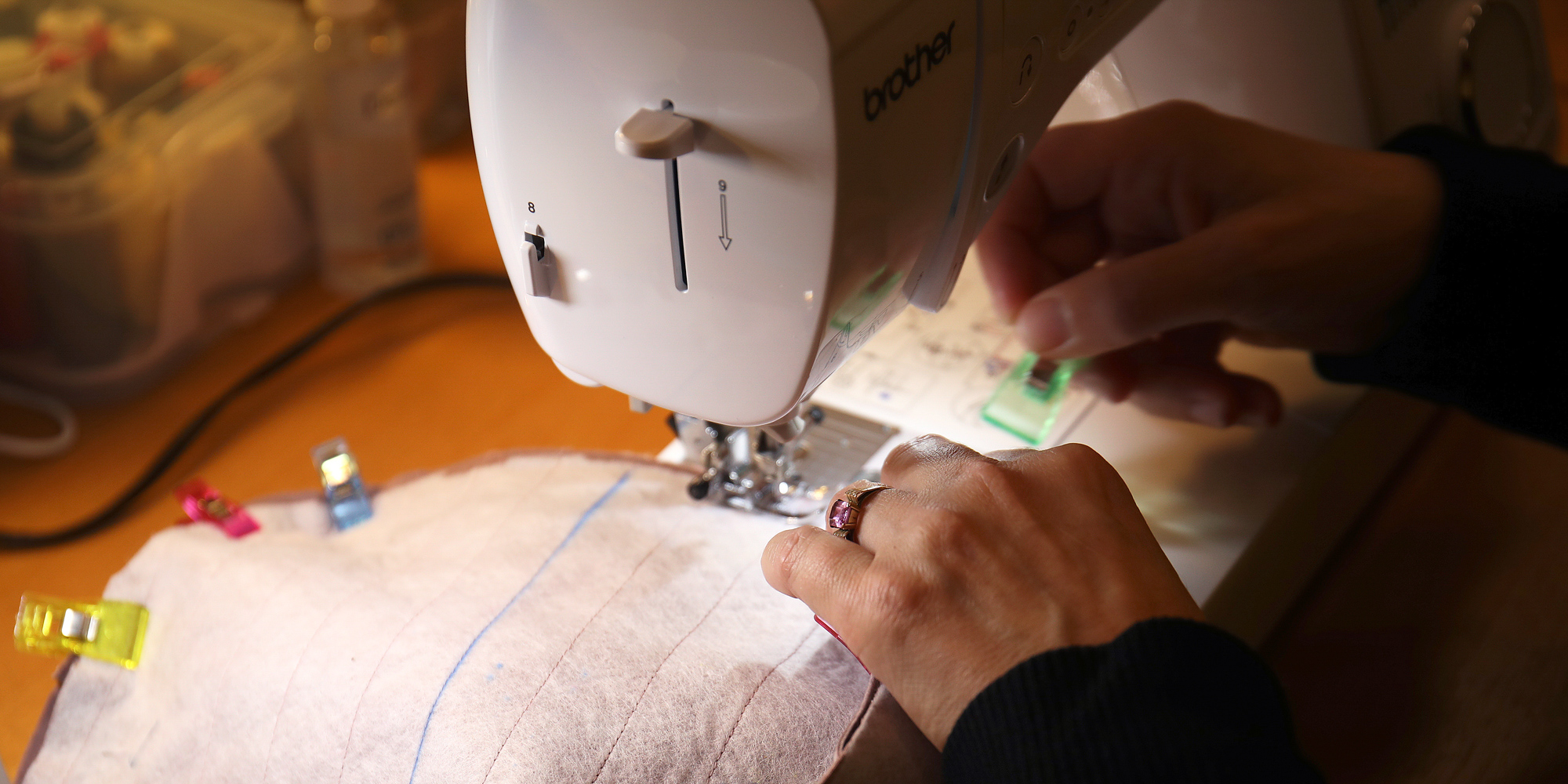 Deltager syr tøj ved symaskine med farverigt stof