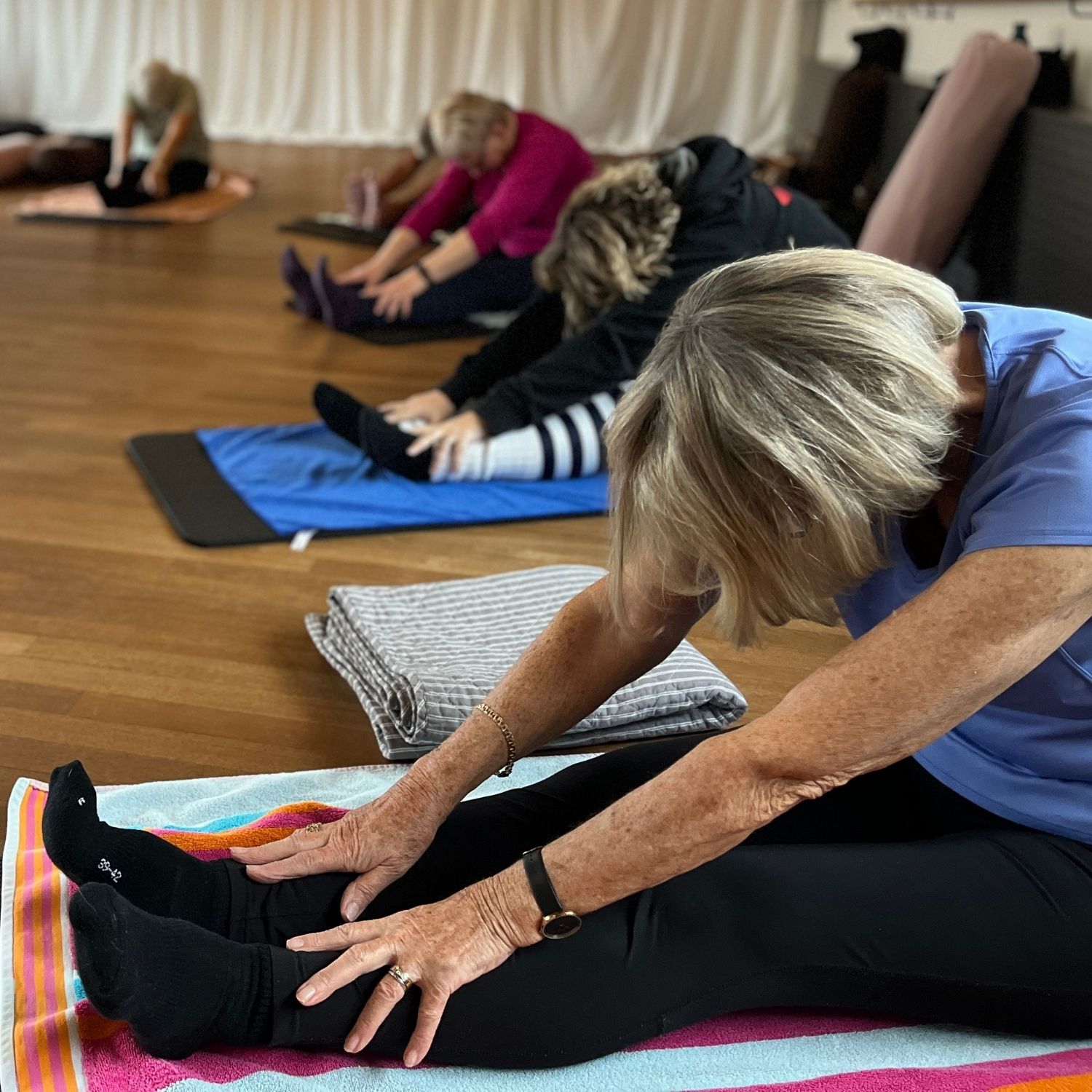 Kursister der laver yoga øvelser på yogamåtter i afslappet træningstøj