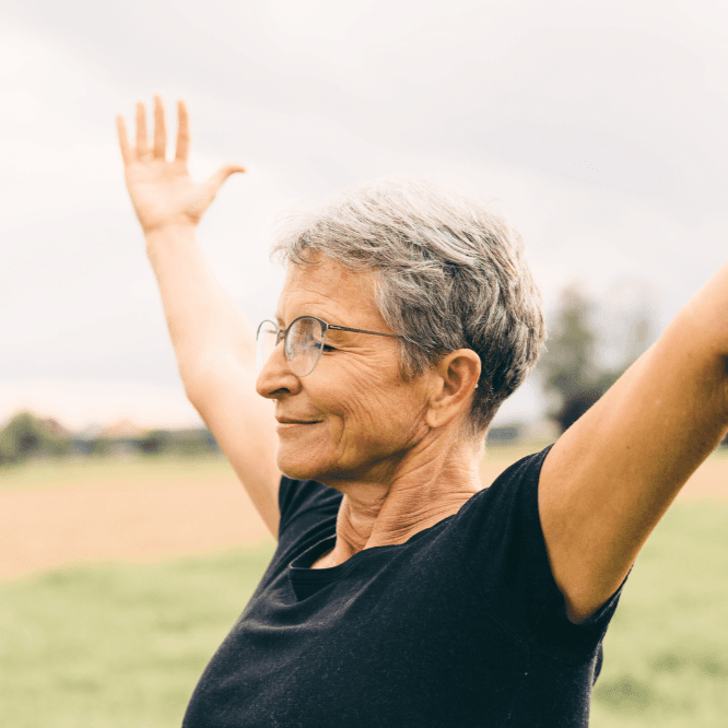 Kvinde står ude og strækker arme