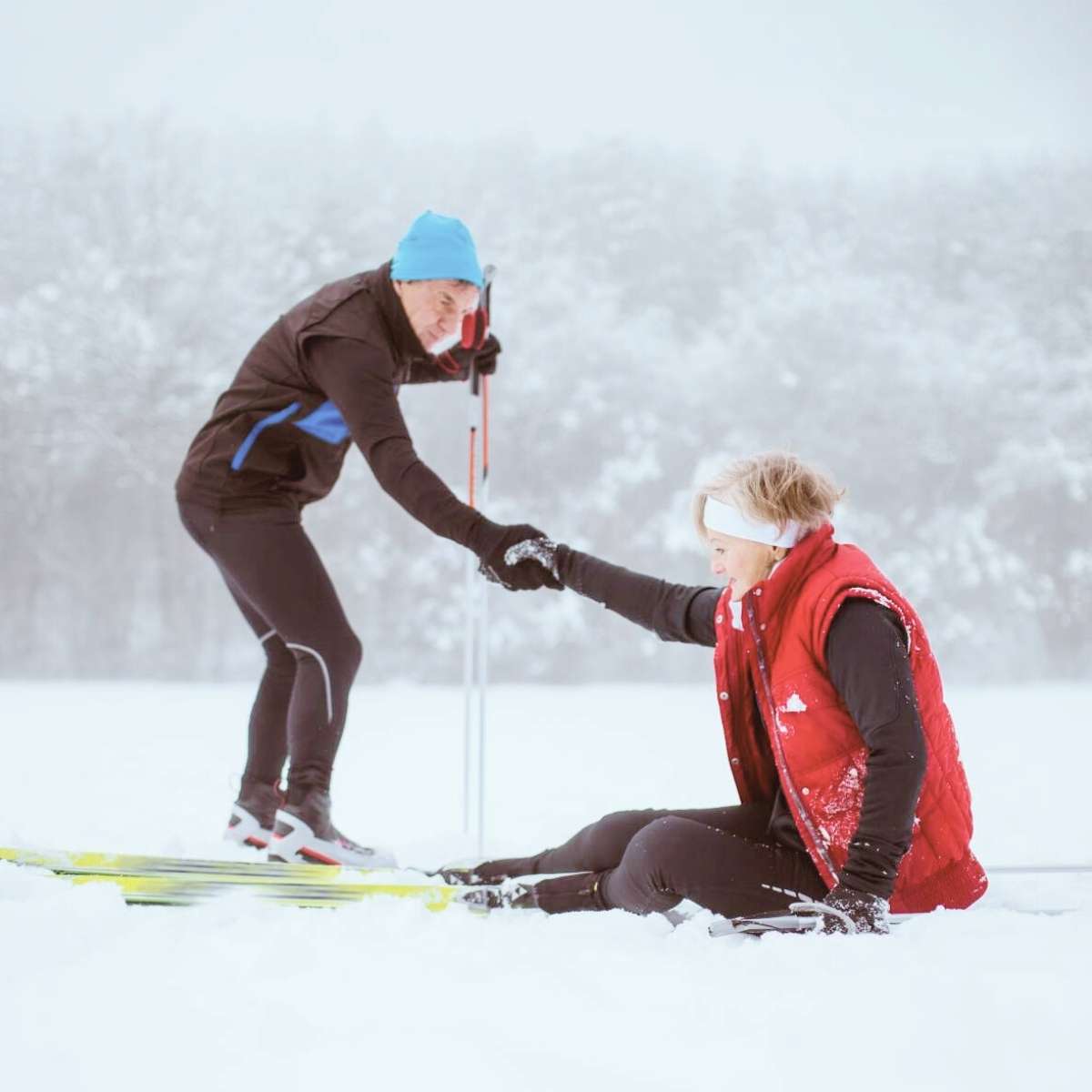 En mand hjælper en kvindelig skiløber op fra sneen