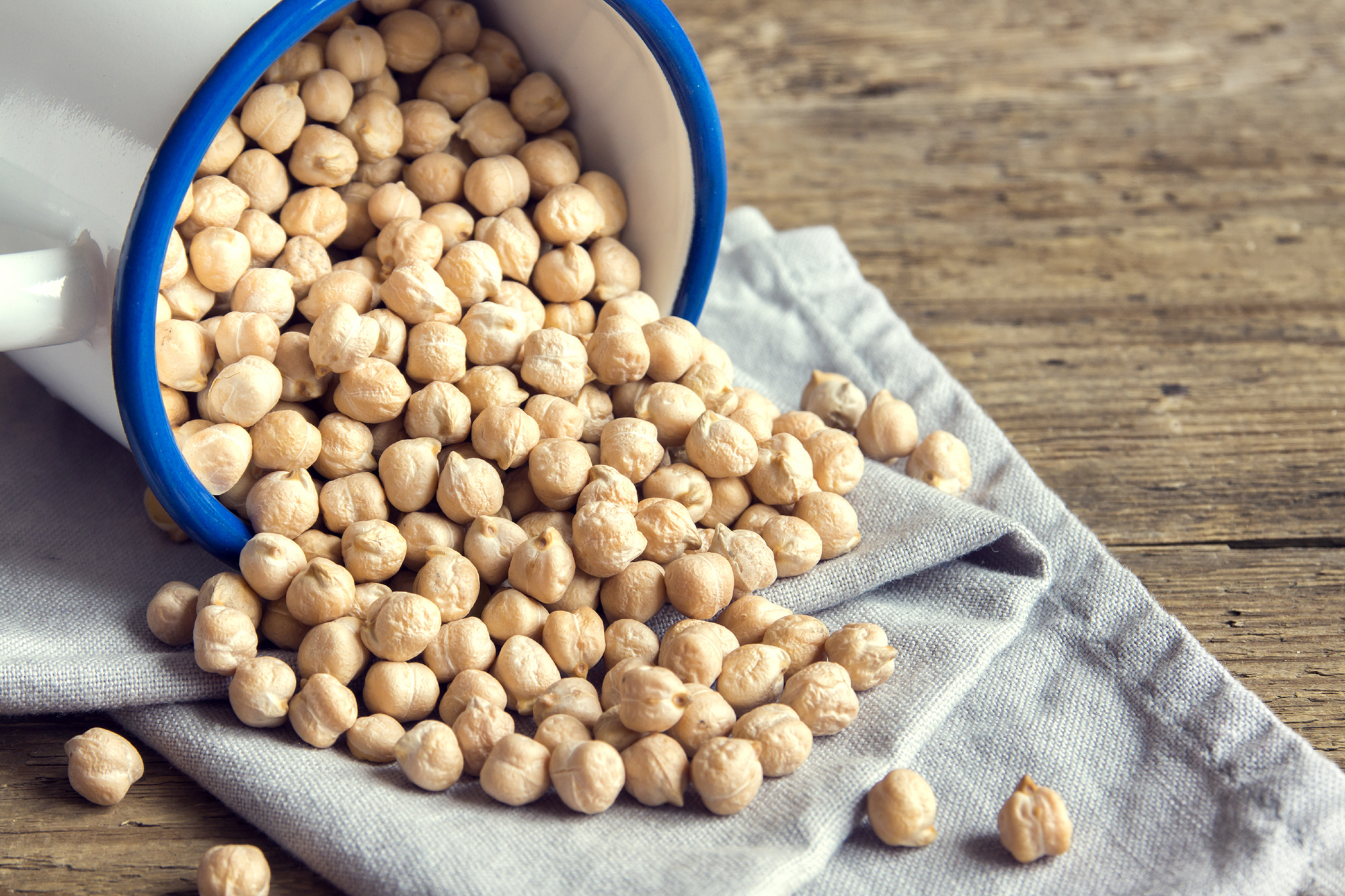 Tørrede kikærter i en hvid skål med blå kant på et træbord