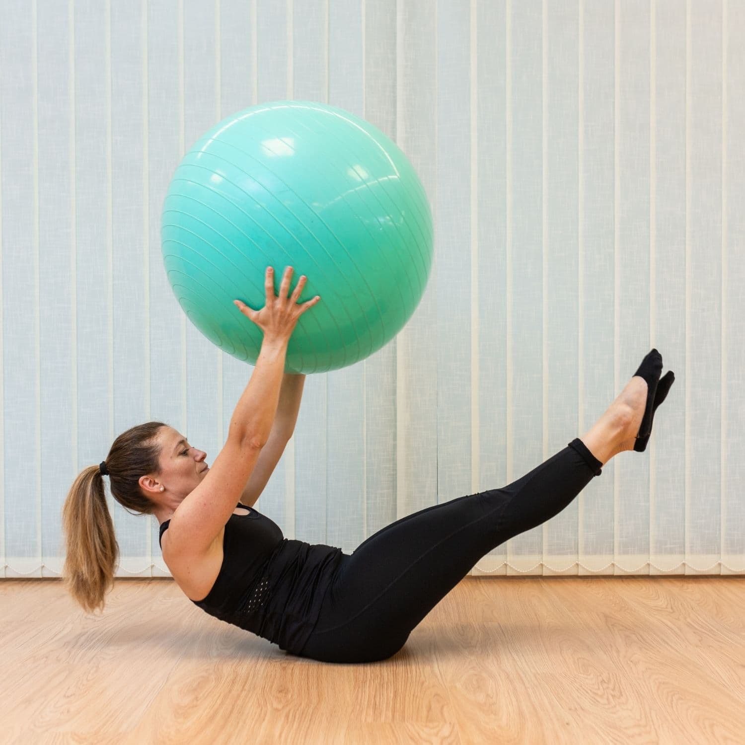 Deltager udfører skånsom pilatesøvelse på bold på hensyntagende hold.