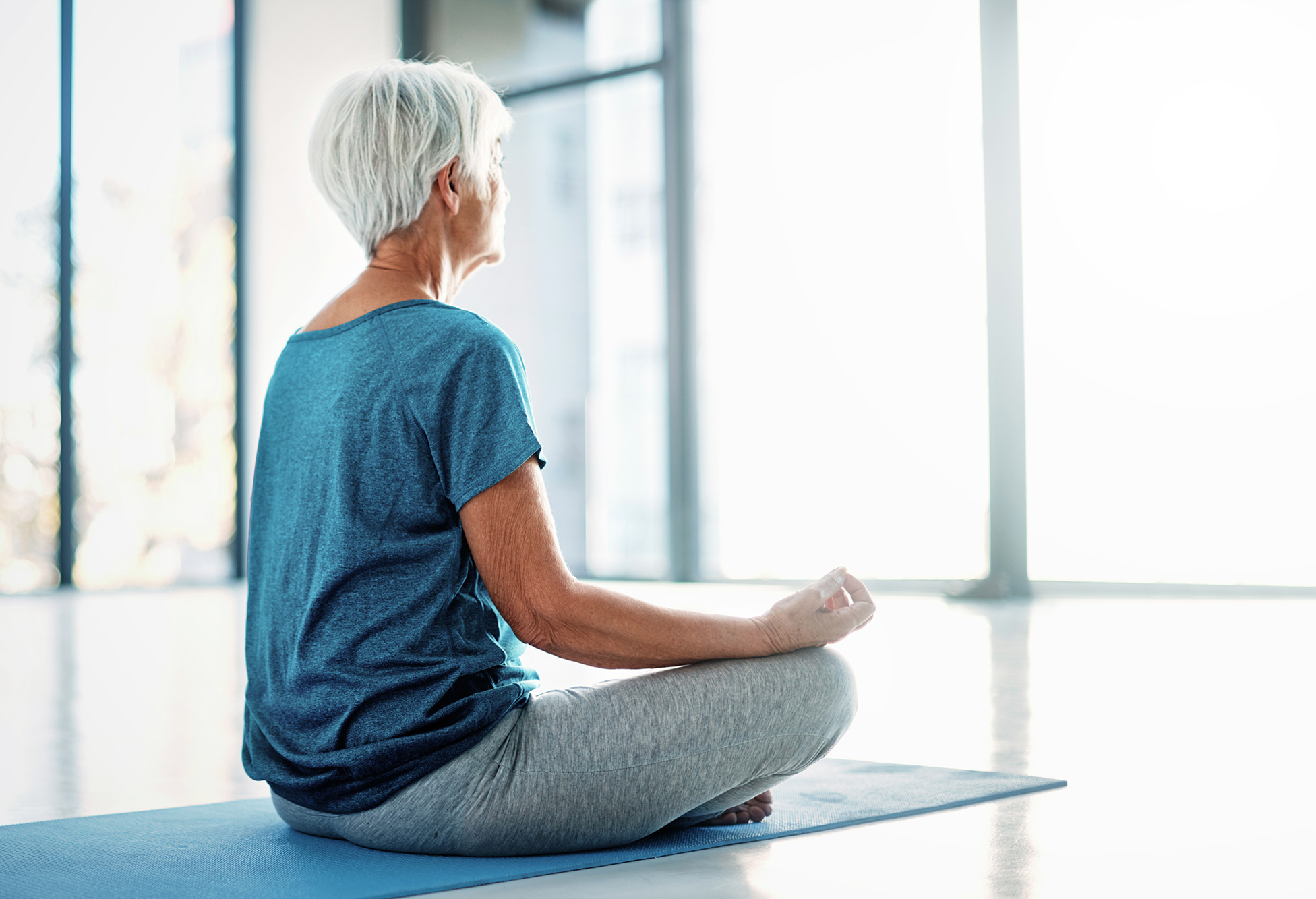 Senior sidder i yogastilling og meditere