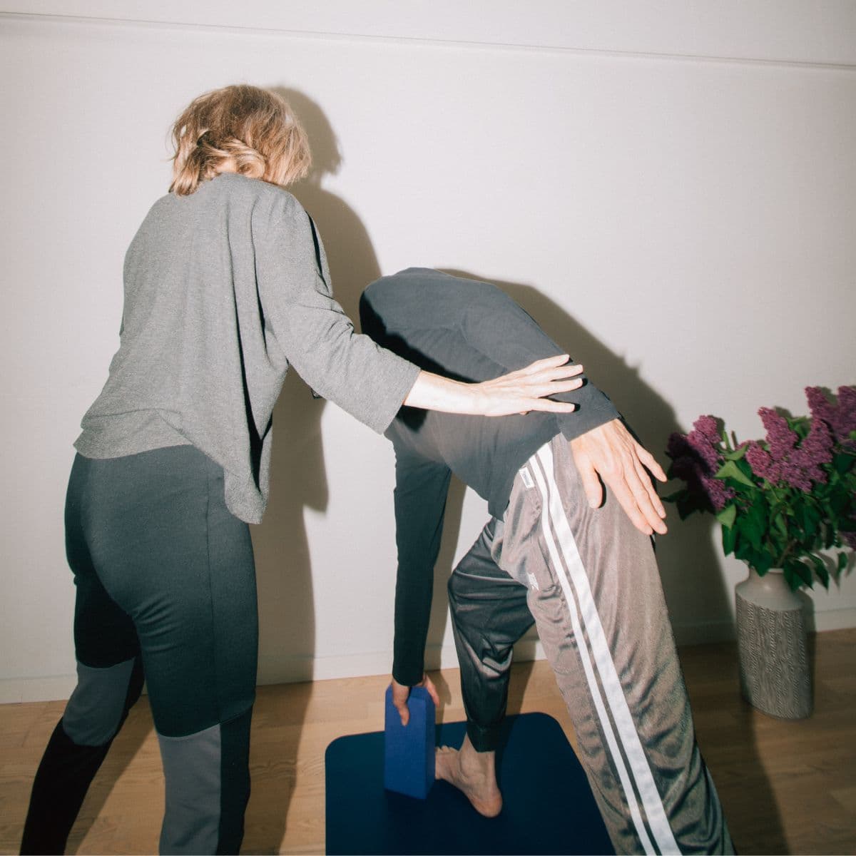 Underviser hjælper kursist i yogastilling