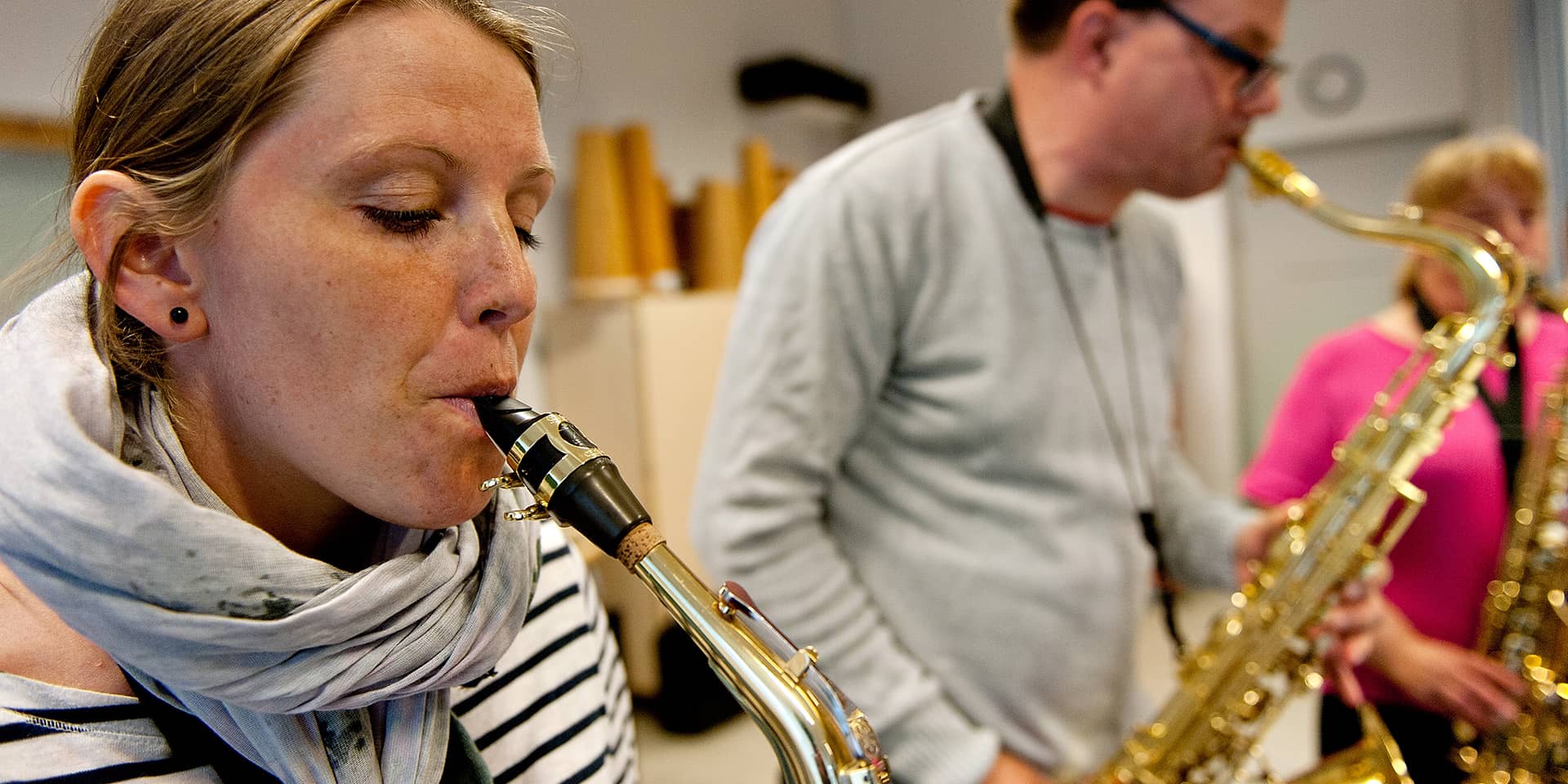 En kvinde og en mand, der blæser i saxofoner, til musikundervisning i saxofoner for begyndere og letøvede i FOF Aarhus