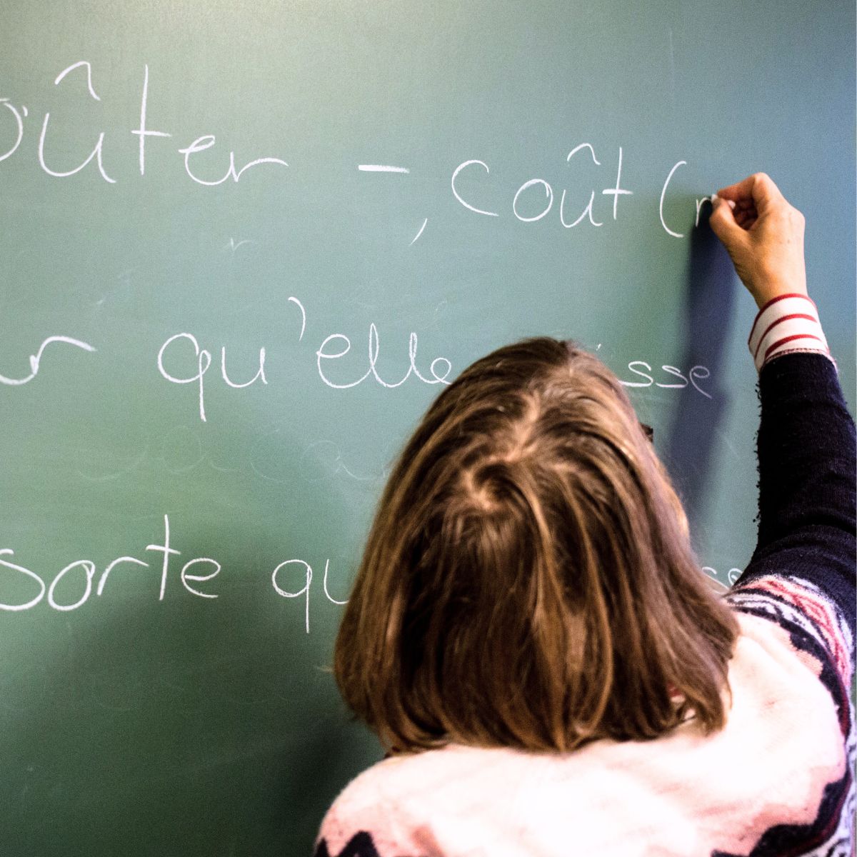 Underviser med ryggen til der skriver på tavlen