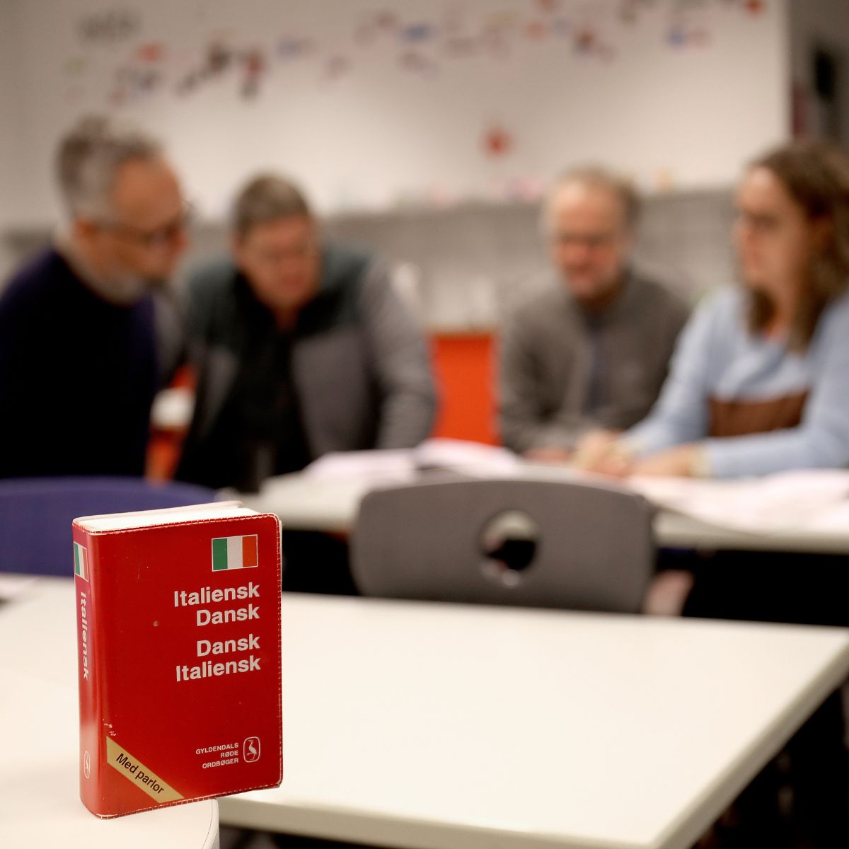 Deltagere på italienskkursus med italiensk ordbog i forgrunden.