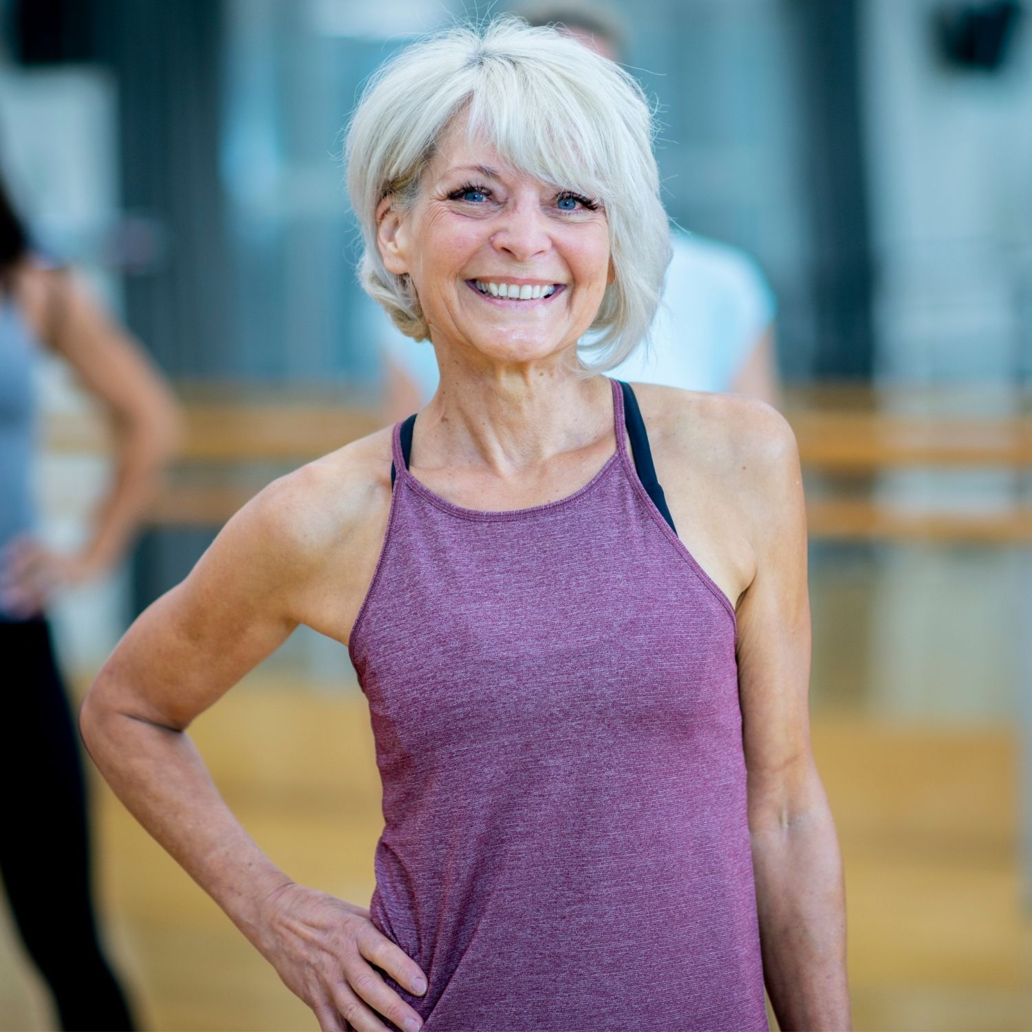 Kvindelig kursist der smiler i træningstøj med hånden på hoften