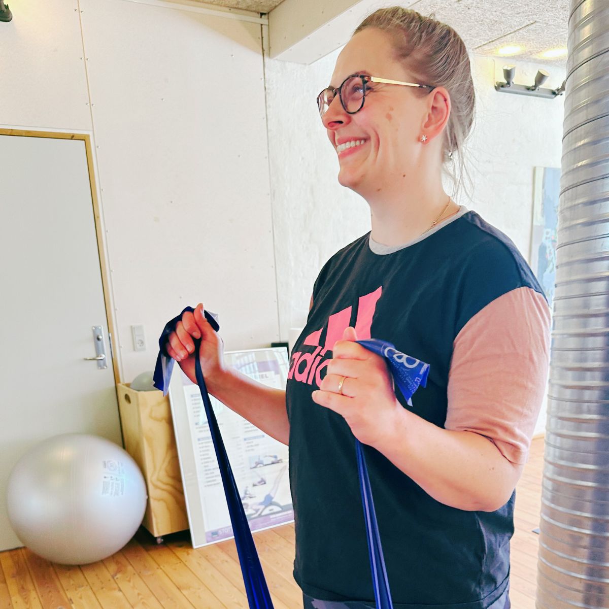 smilende kvinde trækker i elastik til Pilates