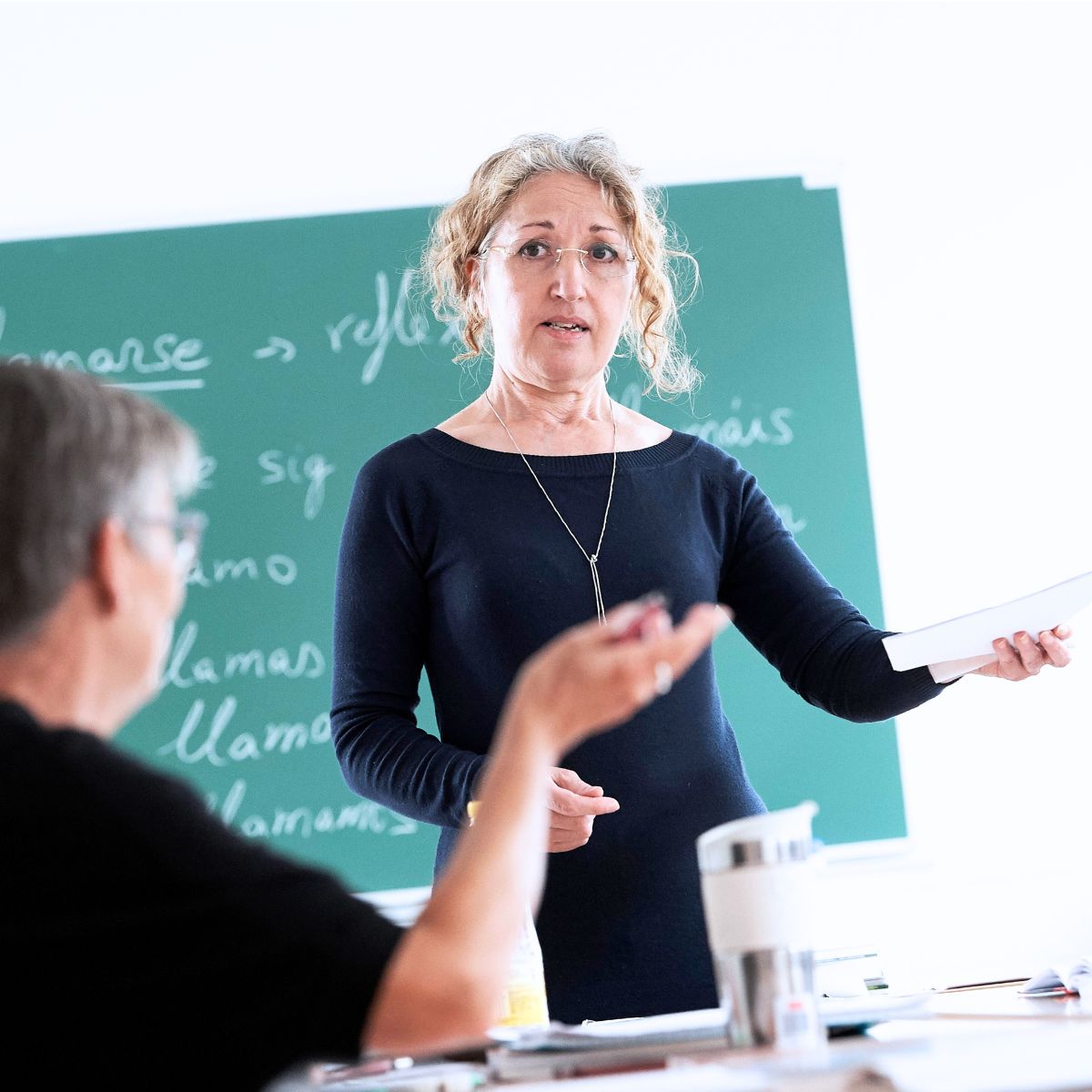 Spanskunderviser ved tavle der snakker med en kursist