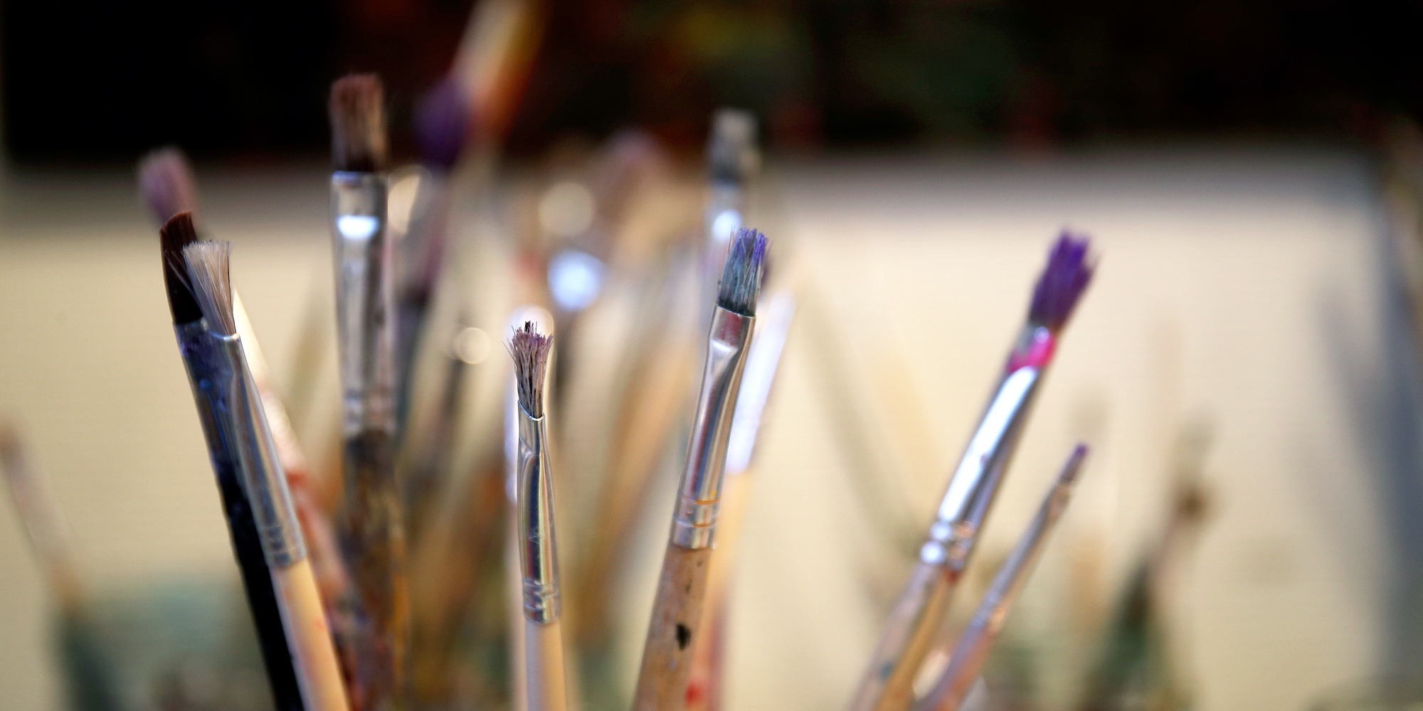 Deltager arbejder med akrylfarver på lærred i atelier