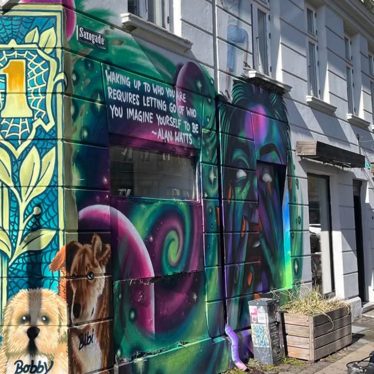 En guide leder en gruppe gennem en Vesterbro-baggård med gamle murstensbygninger, farverige gavlmalerier og grønne kroge.