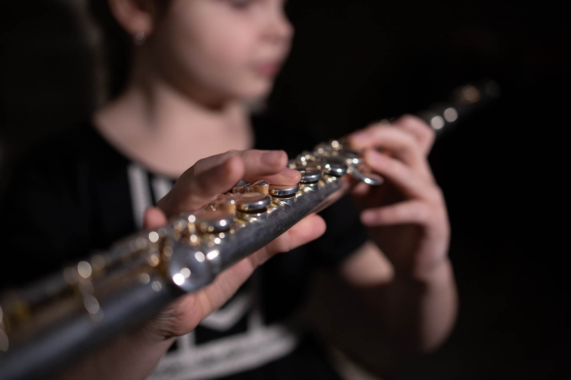 Person spiller på tværfløjte med fokus på hænder og instrument