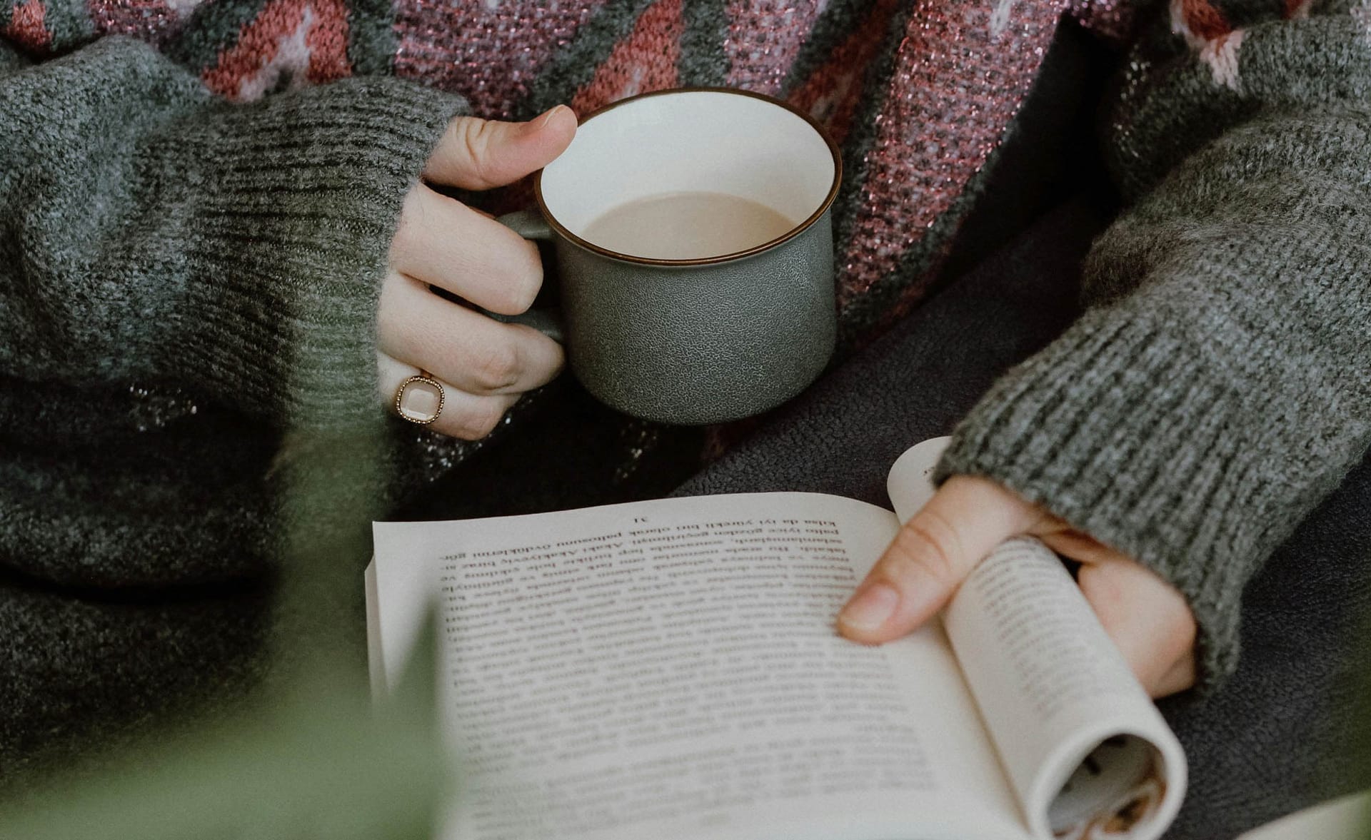 Skrivekursus i vinterferien kvinde læser en bog og drikker en varm kop kaffe