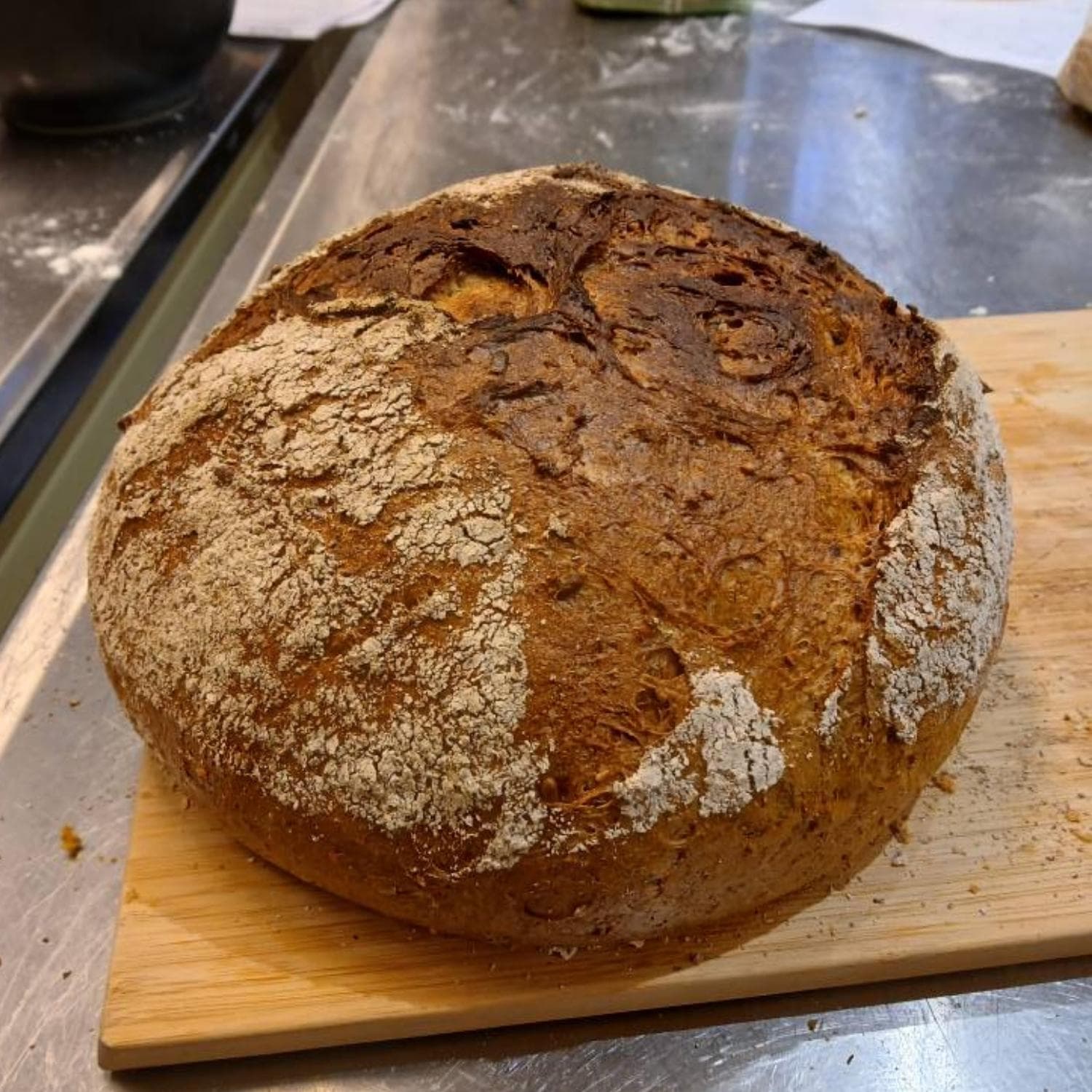 Friskbagt groft surdejsbrød på et skærebræt - lavet af John Bramsen